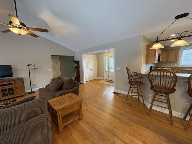 living room featuring vaulted ceiling, ceiling fan, and light hardwood / wood-style floors