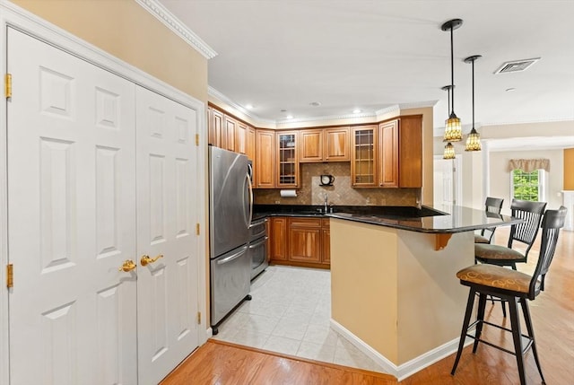 190 Chickering Rd Unit 201D, North Andover, MA 01845 - kitchen featuring freestanding refrigerator, brown cabinetry, crown molding, a kitchen bar, and a peninsula