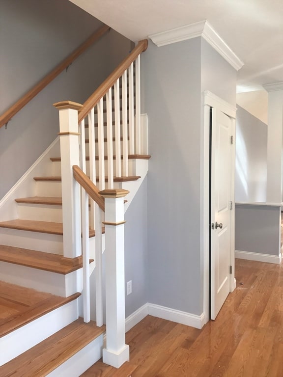 staircase featuring ornamental molding and light hardwood / wood-style floors