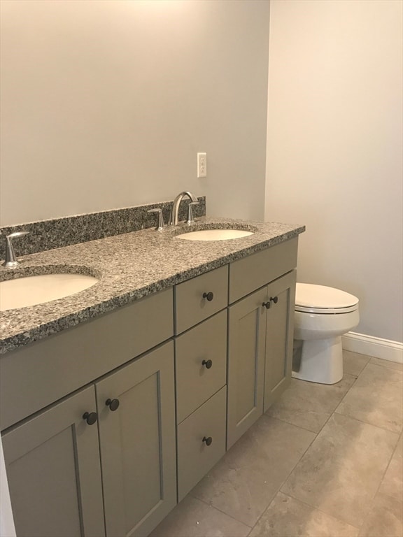 bathroom with double vanity, toilet, and tile floors