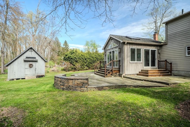 exterior space featuring a chimney, an outbuilding, roof mounted solar panels, a yard, and a patio