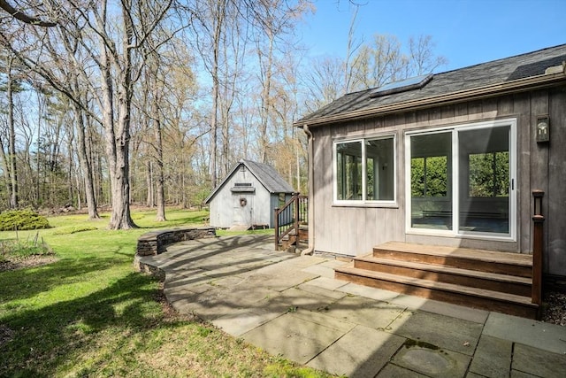 view of side of home with a lawn, an outbuilding, roof mounted solar panels, a patio, and entry steps