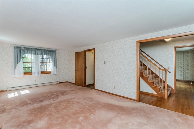 unfurnished room featuring baseboard heating, stairs, wood finished floors, baseboards, and wallpapered walls