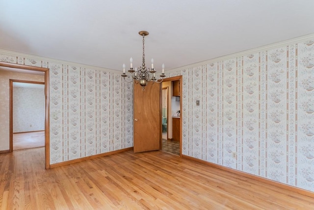 empty room featuring baseboards, wood finished floors, and a chandelier