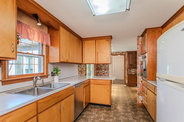 kitchen with light countertops, stainless steel appliances, a sink, and a peninsula