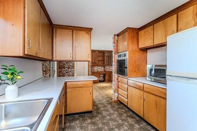 kitchen with brown cabinets, light countertops, a sink, a peninsula, and stainless steel appliances