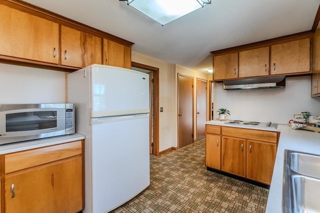 kitchen with light countertops, under cabinet range hood, white appliances, and a sink