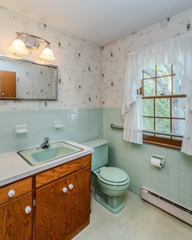 bathroom with tile walls, baseboard heating, vanity, a wainscoted wall, and wallpapered walls