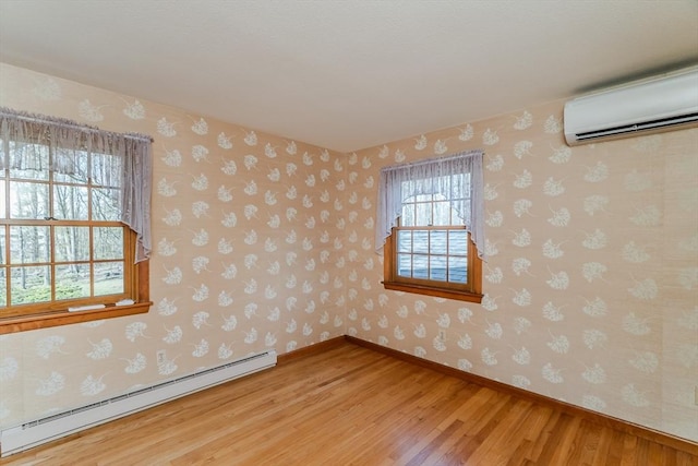 spare room featuring light wood-type flooring, a baseboard radiator, baseboards, and an AC wall unit