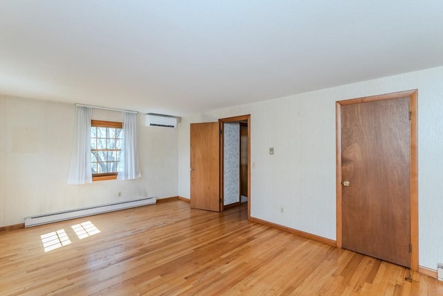spare room featuring baseboards, baseboard heating, a wall unit AC, and wood finished floors