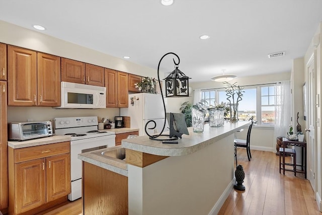 kitchen featuring light countertops, white appliances, visible vents, and a kitchen island