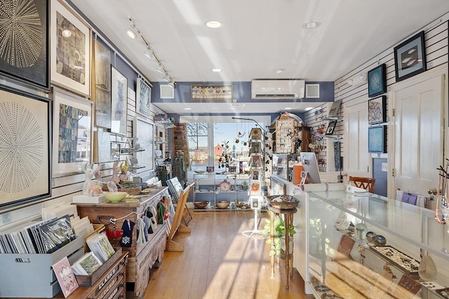 interior space with recessed lighting, glass insert cabinets, light wood-style floors, an AC wall unit, and track lighting