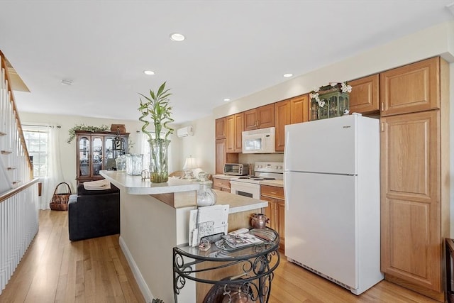 kitchen featuring white appliances, light countertops, a center island, light wood finished floors, and brown cabinetry