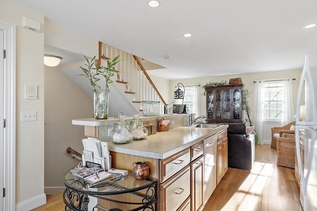 kitchen with dishwasher, light wood-style flooring, open floor plan, freestanding refrigerator, and light countertops