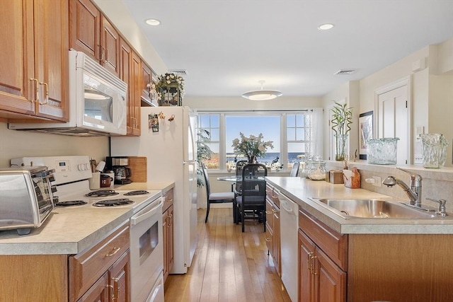 kitchen with white appliances, light wood-style floors, light countertops, and a sink