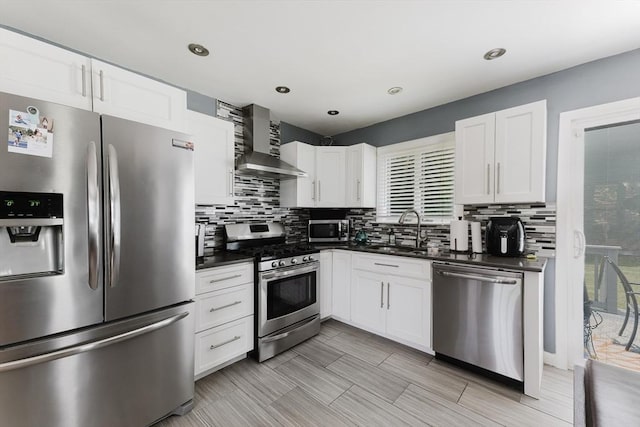 11 Ann Ave, Dartmouth, MA 02747 - kitchen featuring stainless steel appliances, wall chimney range hood, dark countertops, tasteful backsplash, and white cabinets