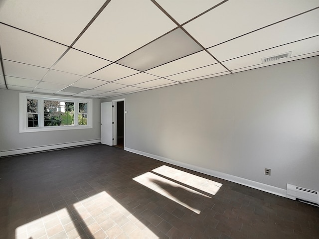 unfurnished room with a paneled ceiling and a baseboard heating unit