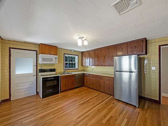 kitchen with appliances with stainless steel finishes, sink, and light wood-type flooring