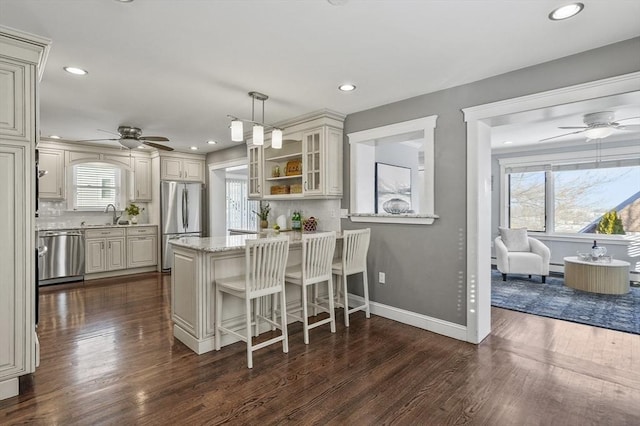 kitchen featuring a kitchen breakfast bar, appliances with stainless steel finishes, kitchen peninsula, pendant lighting, and sink