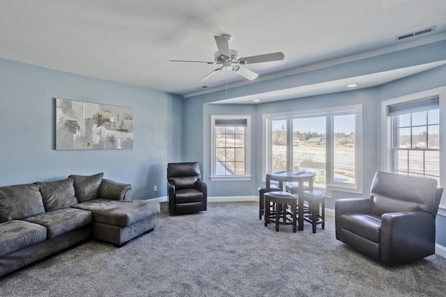 carpeted living area with a ceiling fan, baseboards, visible vents, and a wealth of natural light