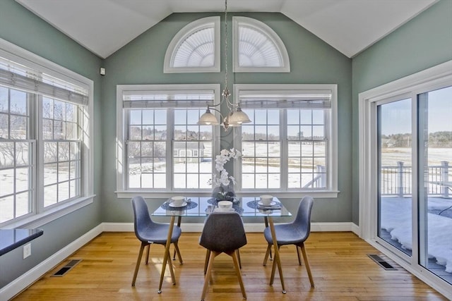 dining room featuring wood finished floors, visible vents, baseboards, vaulted ceiling, and an inviting chandelier