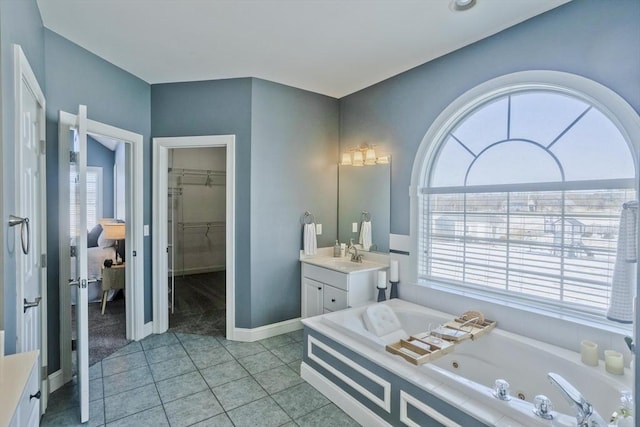 full bath featuring a healthy amount of sunlight, vanity, a tub with jets, and tile patterned floors