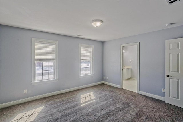 unfurnished bedroom featuring ensuite bath, carpet, visible vents, and baseboards