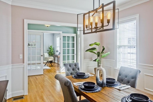 dining room featuring wainscoting, visible vents, and crown molding