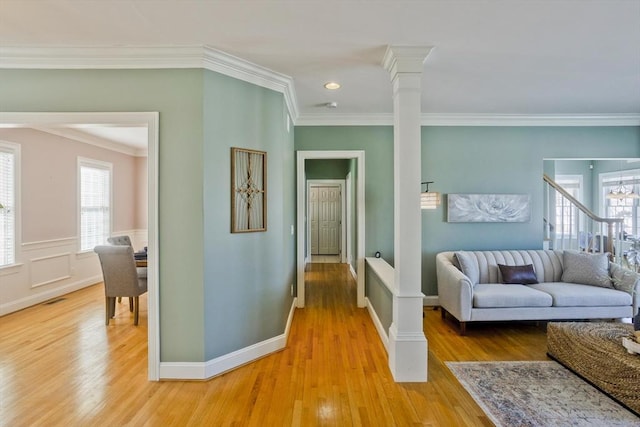 hallway with crown molding, ornate columns, visible vents, light wood-style flooring, and baseboards