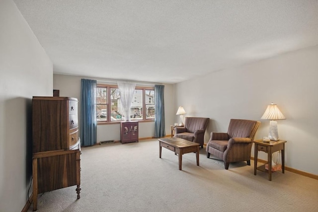 sitting room with carpet floors, visible vents, baseboards, and a textured ceiling