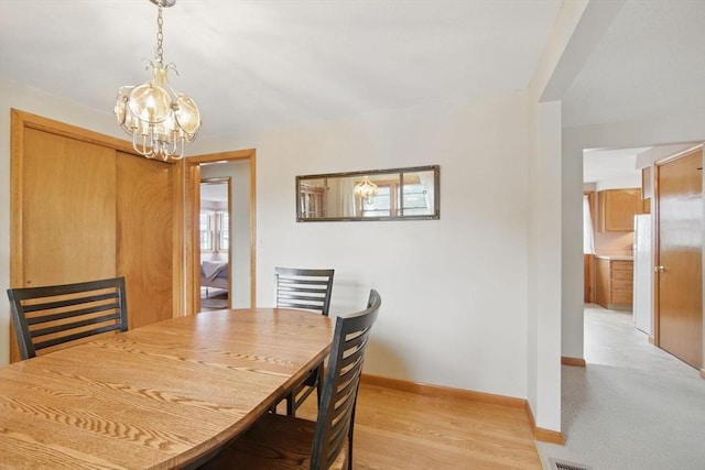 dining room with a notable chandelier, light wood-style flooring, and baseboards