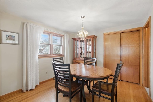 dining area featuring baseboards, an inviting chandelier, and light wood-style floors