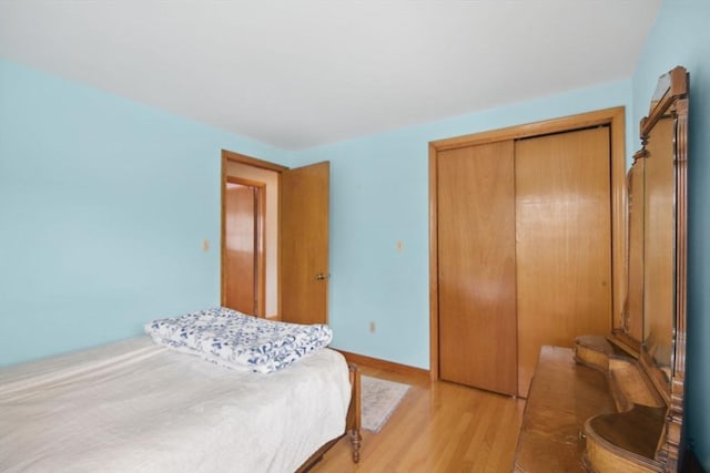 bedroom with light wood finished floors, baseboards, and a closet