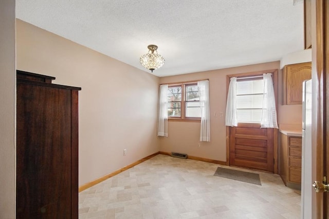 interior space with visible vents, a notable chandelier, a textured ceiling, and baseboards