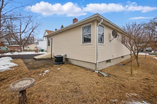 view of side of property with a chimney and central AC unit