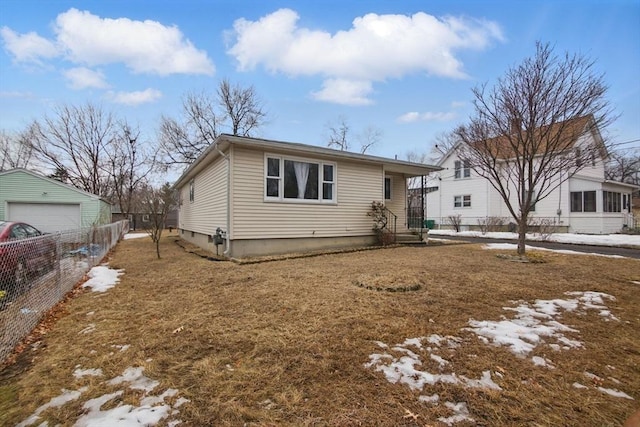 view of front facade featuring a detached garage, fence, and an outbuilding