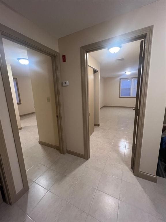 hall with baseboards and light tile patterned flooring