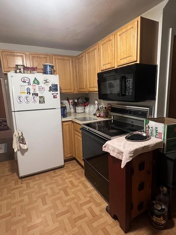 kitchen with black appliances, light brown cabinetry, and light countertops