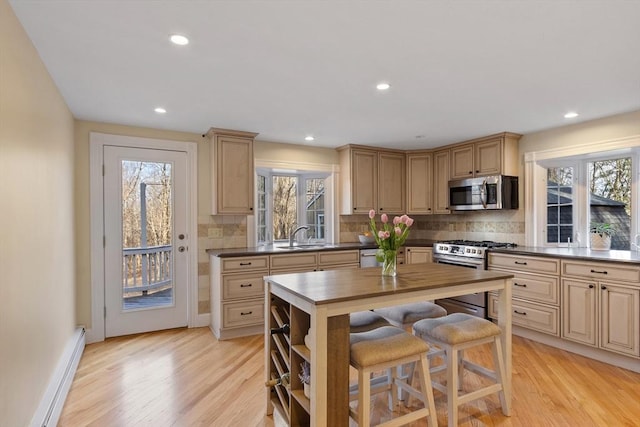 kitchen featuring light wood-style flooring, recessed lighting, appliances with stainless steel finishes, decorative backsplash, and baseboard heating