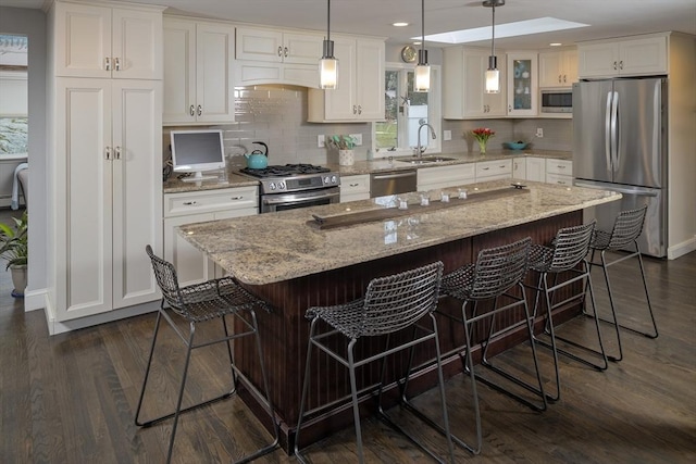 kitchen with sink, a breakfast bar area, a center island, appliances with stainless steel finishes, and white cabinets