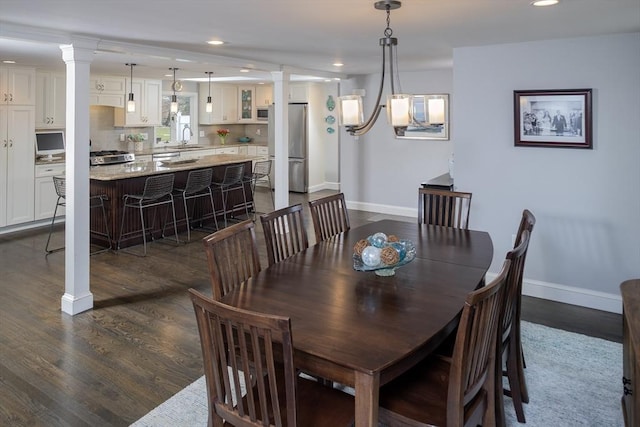 dining area with decorative columns, sink, and dark hardwood / wood-style flooring