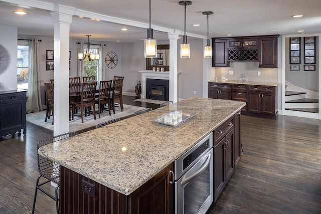 kitchen with pendant lighting, dark hardwood / wood-style floors, a center island, dark brown cabinetry, and oven