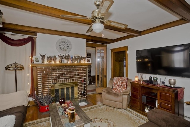 living room featuring a fireplace, beamed ceiling, wood finished floors, and a ceiling fan