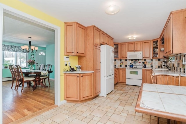 kitchen featuring sink, decorative light fixtures, a chandelier, baseboard heating, and white appliances