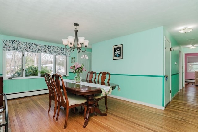 dining room with a baseboard heating unit, a chandelier, and light wood-type flooring