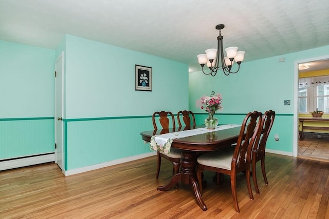 dining area featuring hardwood / wood-style floors, a notable chandelier, and a baseboard heating unit