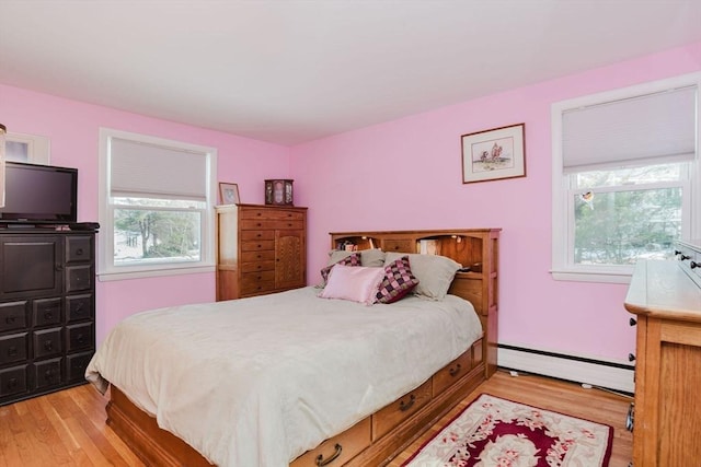 bedroom with a baseboard radiator and light hardwood / wood-style floors