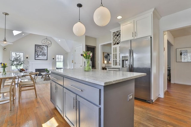 kitchen with open floor plan, a center island, light wood-type flooring, white cabinets, and stainless steel fridge with ice dispenser