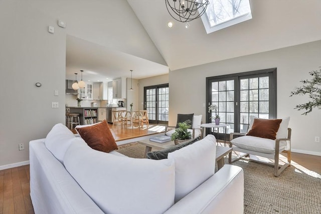 living room with an inviting chandelier, high vaulted ceiling, recessed lighting, baseboards, and wood finished floors