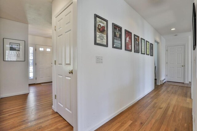 hallway featuring recessed lighting, baseboards, a baseboard heating unit, and light wood-style floors
